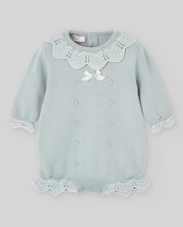 A light sage green baby knit romper with white lace collar, white lace cuffs, a white lace hem, and a small white bow at the chest.