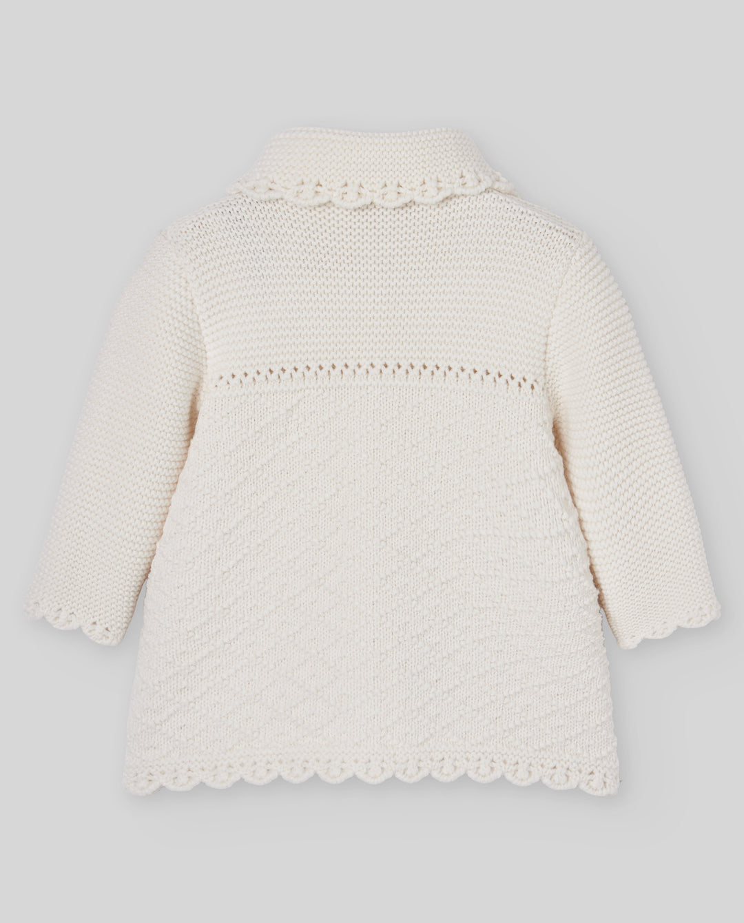 An off-white knitted baby cardigan with long sleeves, a scalloped collar, and a textured pattern on the front, shown against a neutral gray background.