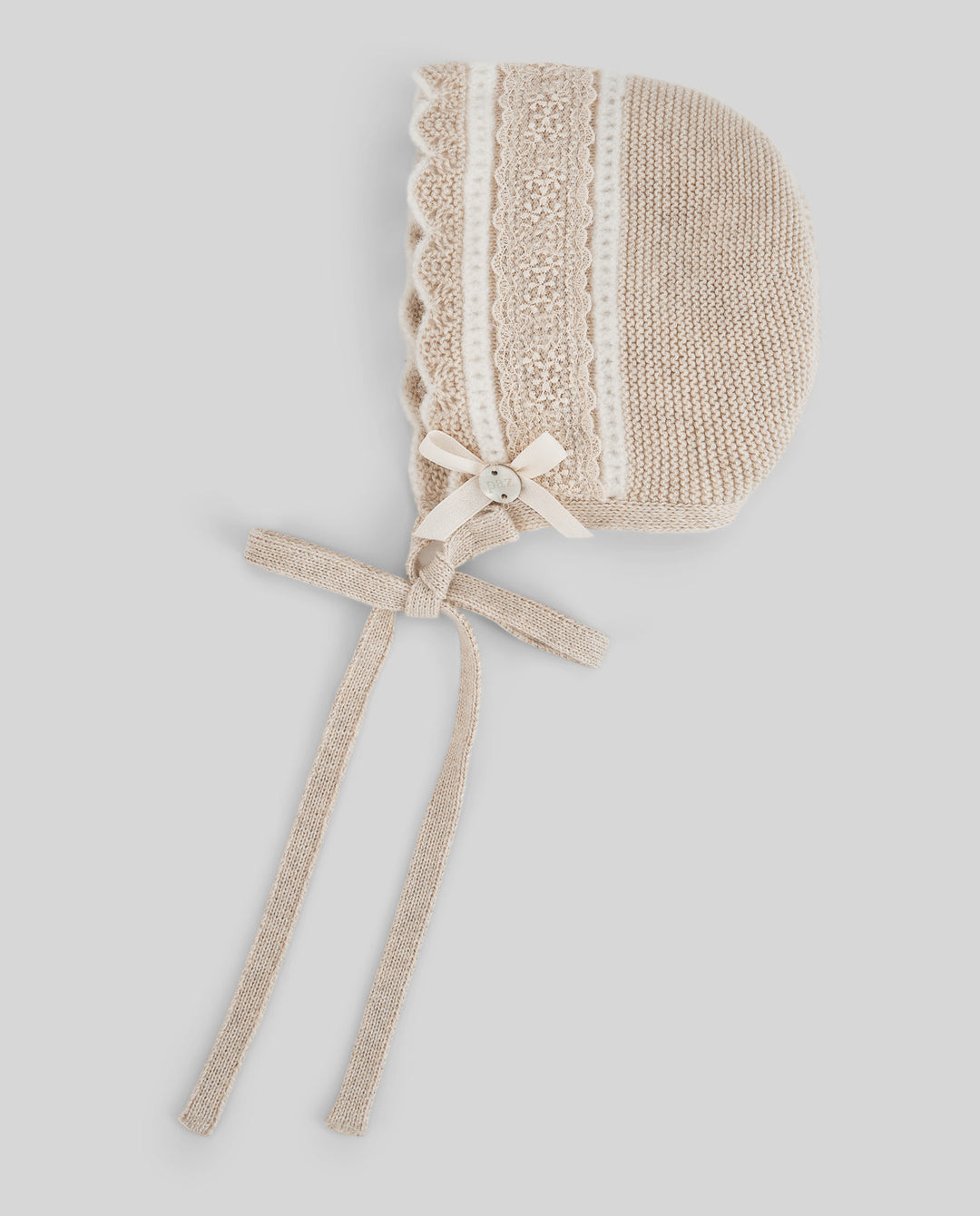 Beige baby bonnet with lace details on a light gray background