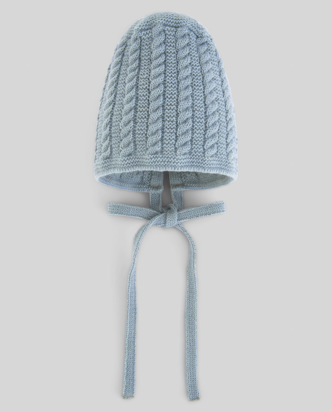 A light blue cable-knit bonnet hat with long ties, shown against a solid light gray background.