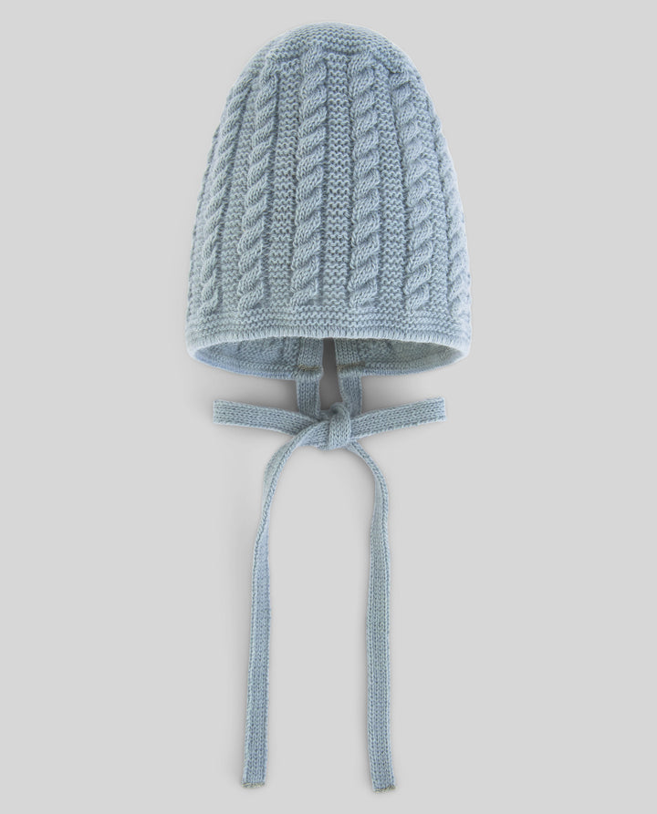 A light blue cable-knit bonnet hat with long ties, shown against a solid light gray background.