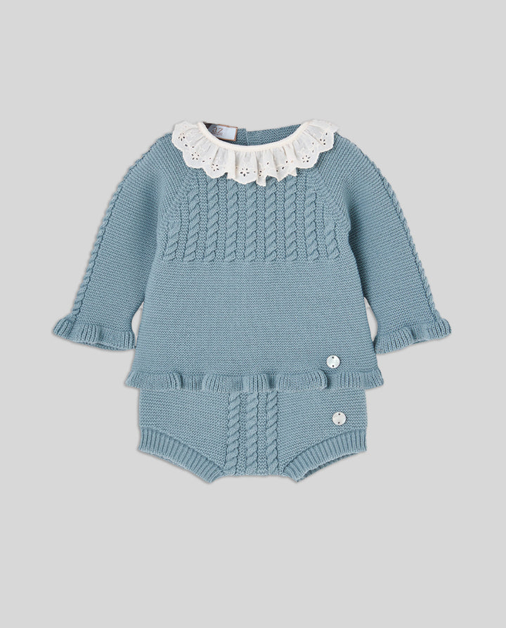 A baby knit two-piece set in dusty blue, featuring a long-sleeve top with a white eyelet ruffled collar and matching ruffle trim, paired with matching ruffle-trimmed bloomers with snap closures.