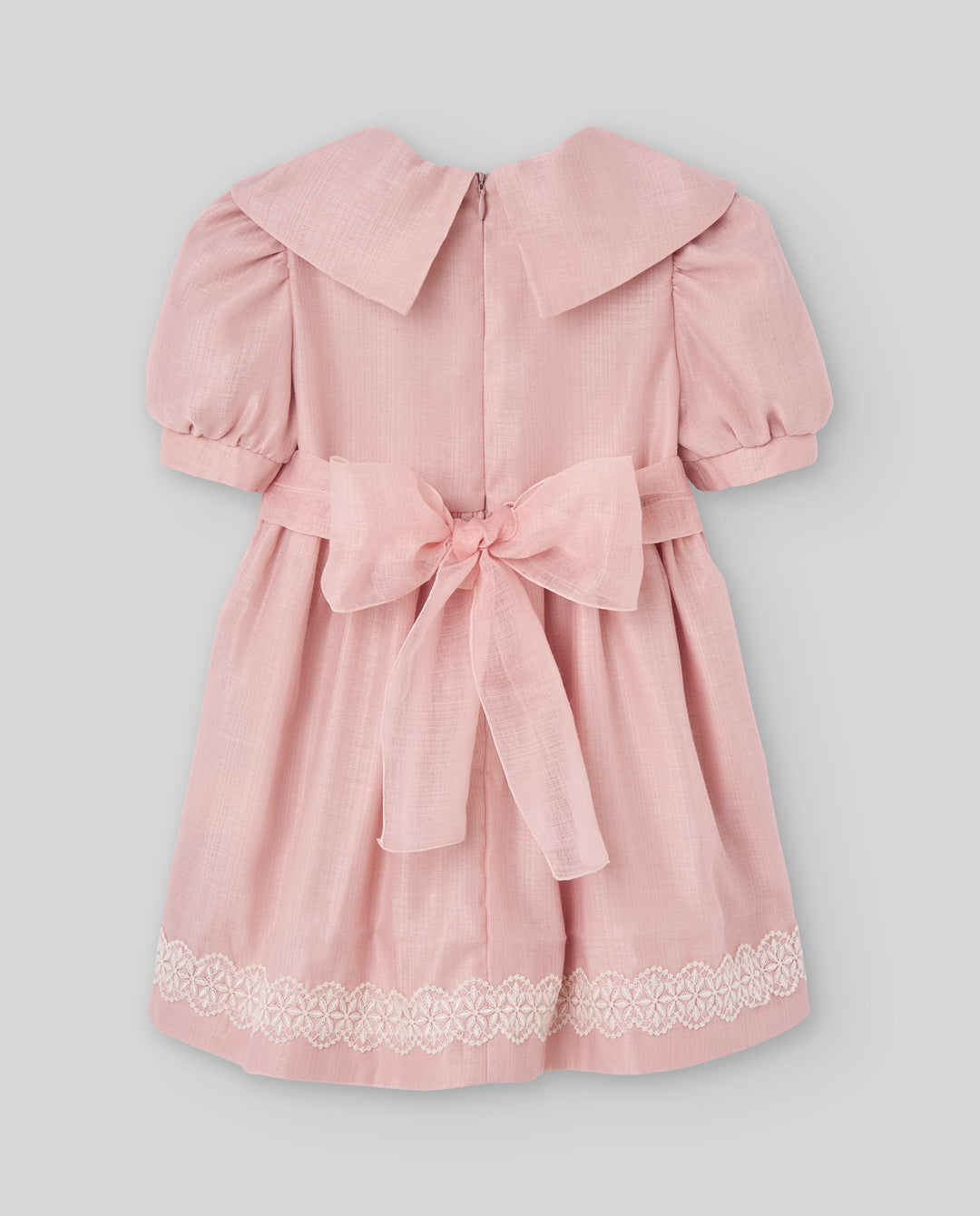 A pink short-sleeve dress for toddlers or girls, featuring a large collar, puff sleeves, a matching fabric tie belt at the waist, and delicate white lace trim along the hem, shown against a solid gray background.