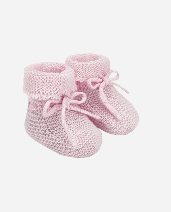 Pair of pink knitted baby booties on a light gray background