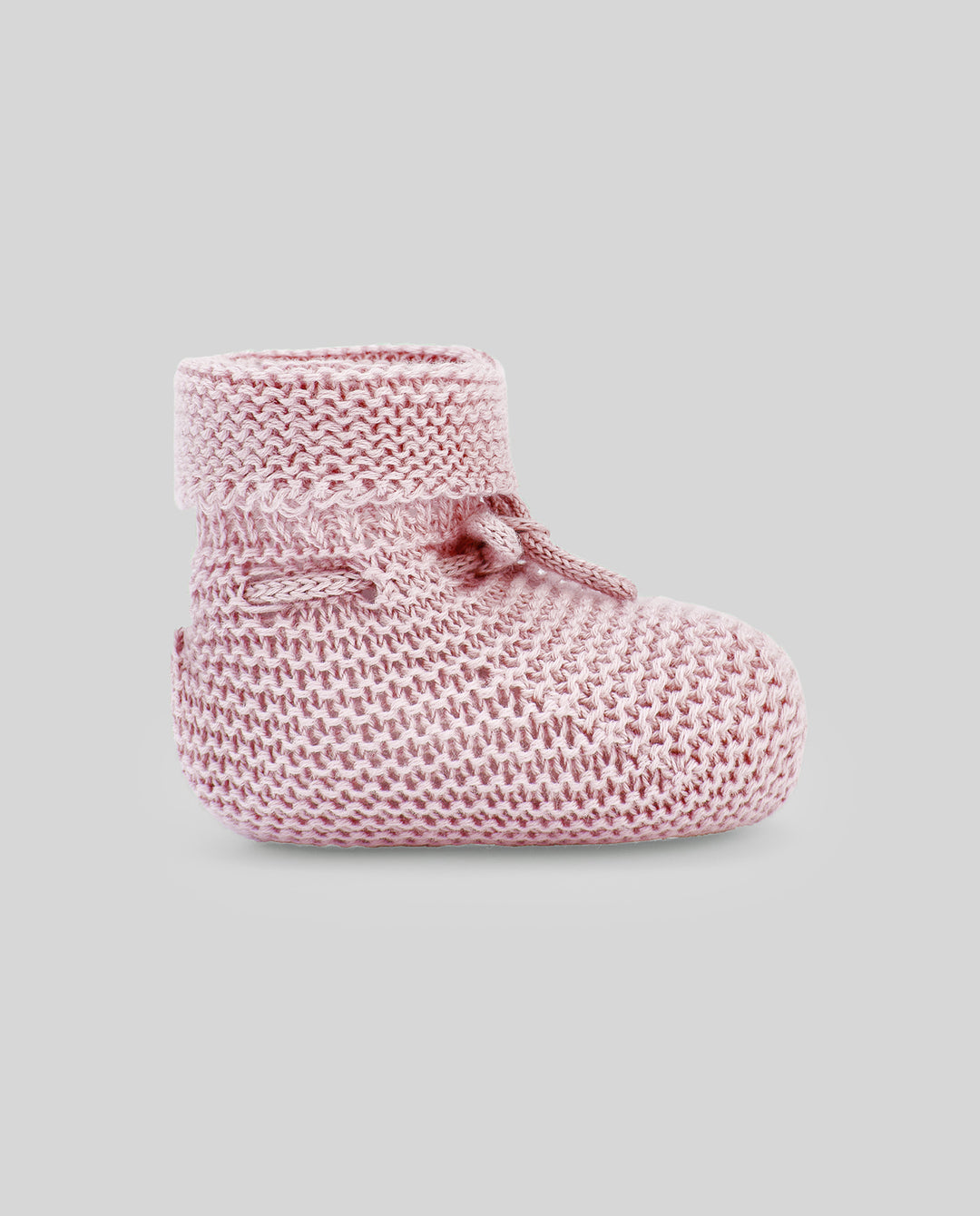 Pink knitted baby bootie on a gray background