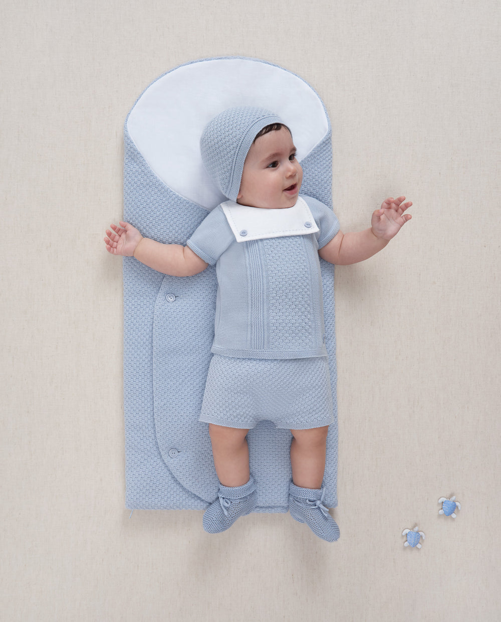 Baby Boy in a Blue Knit 2 Piece outfit laying on a blue blanket