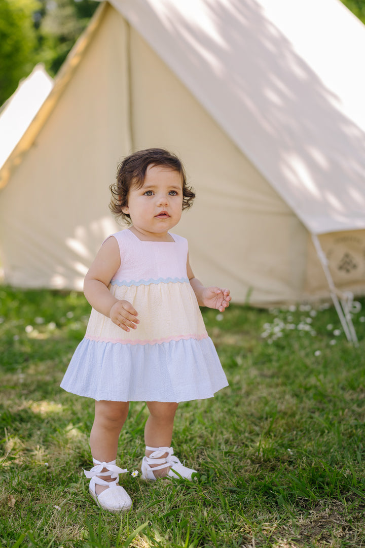 Toddler girl in pastel easter dress standing on grass outside
