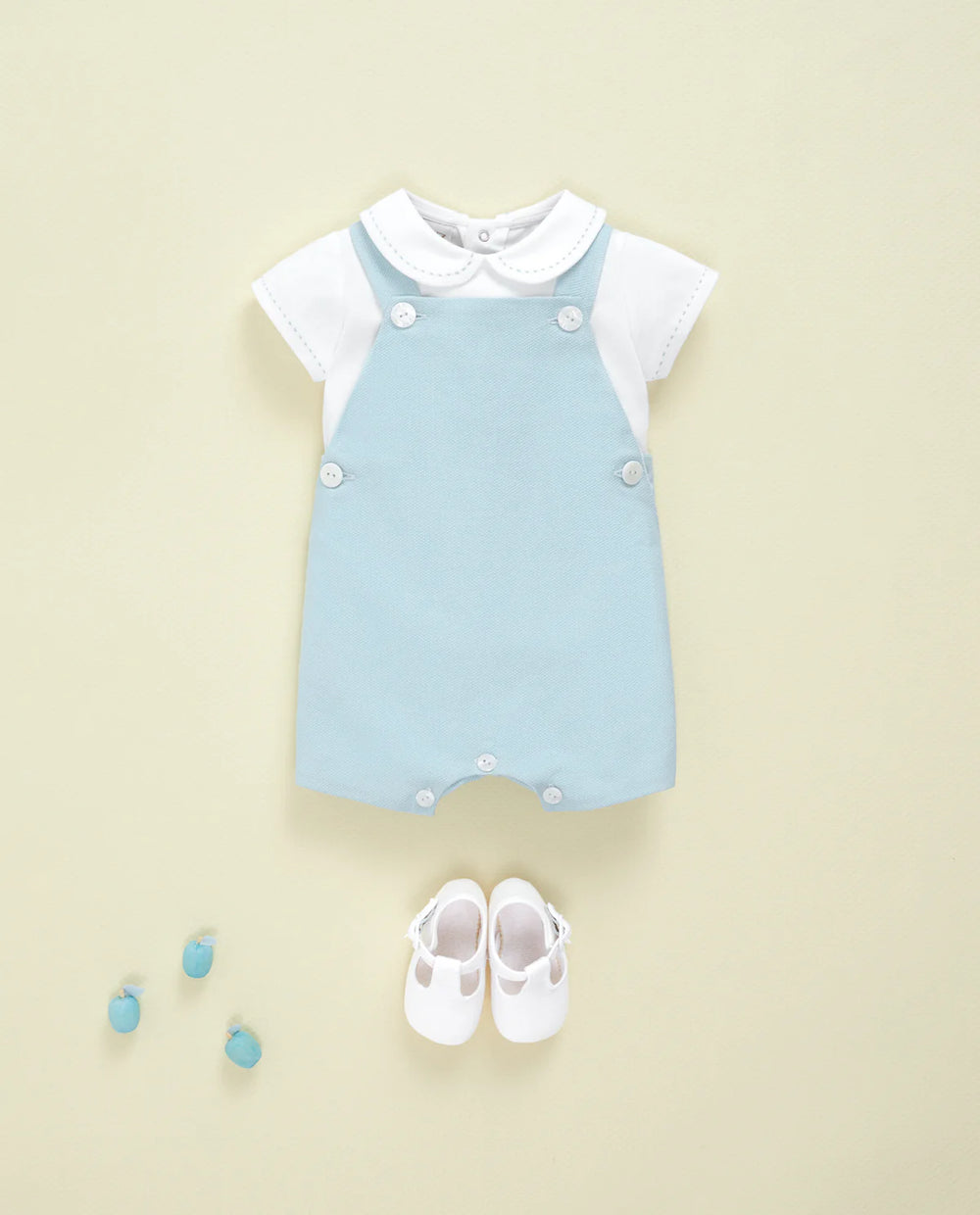 Baby romper with white shirt and shoes on a beige background
