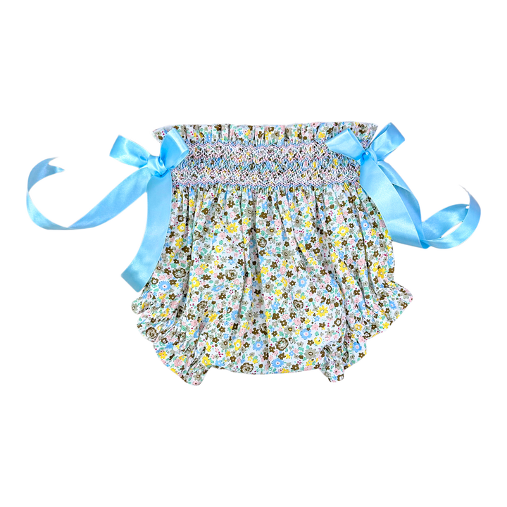 A baby girl's smocked ruffle bloomers featuring a multicolor floral print on a white background with light blue satin side ribbons tied into bows.