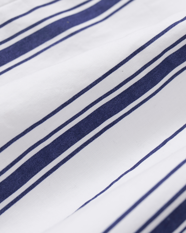 A close-up of white fabric with repeating diagonal navy blue stripes.
