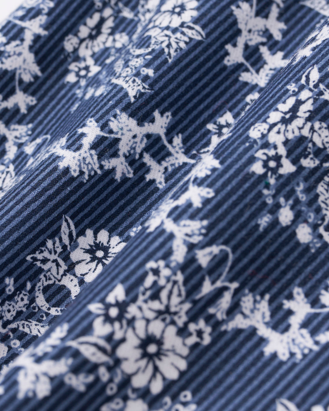 Close-up of a navy blue and white striped fabric with a white floral and deer pattern, showing the texture and weave.