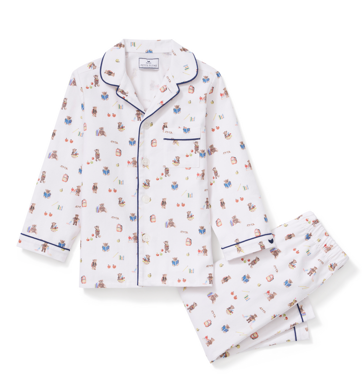A two-piece pajama set featuring a long-sleeve button-front top and matching pants. The pajamas are white with a small, all-over teddy bear pattern in muted red, blue, and brown, and are finished with dark blue piping along the collar, cuffs, and front placket.