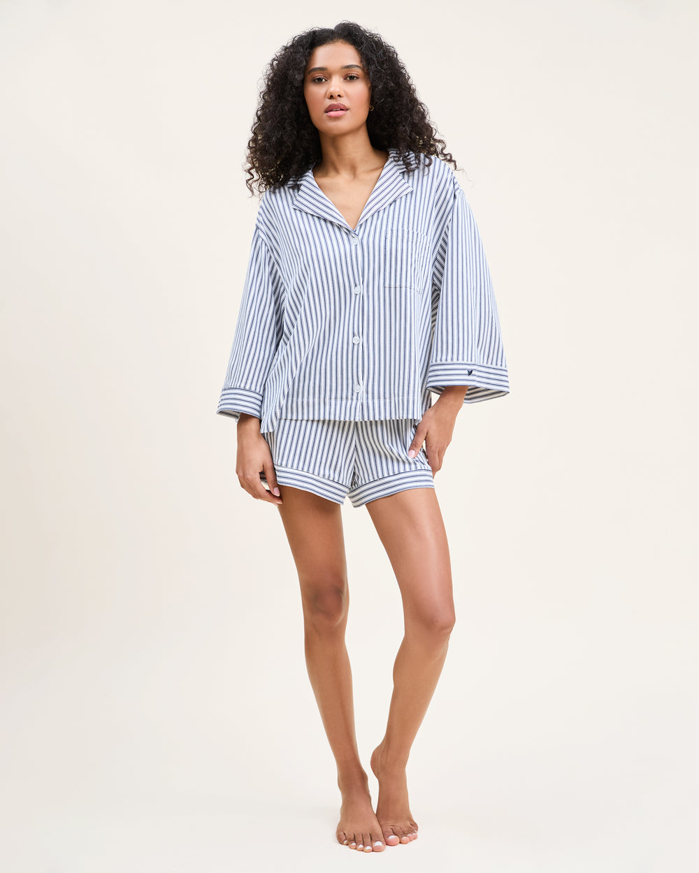 Woman wearing a blue and white striped pajama set on a beige background