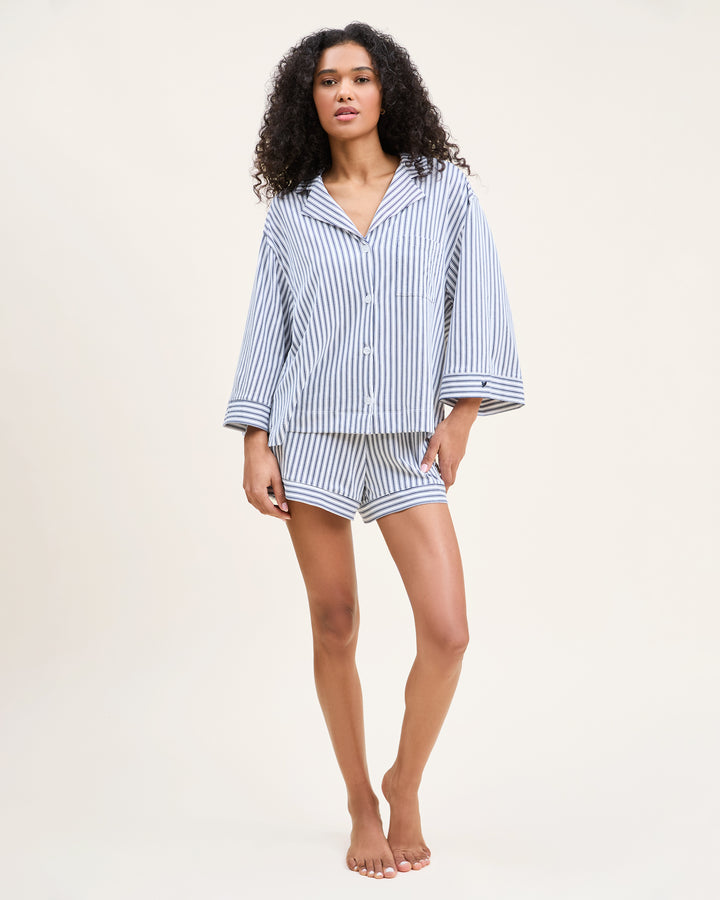 Woman wearing a blue and white striped pajama set on a beige background