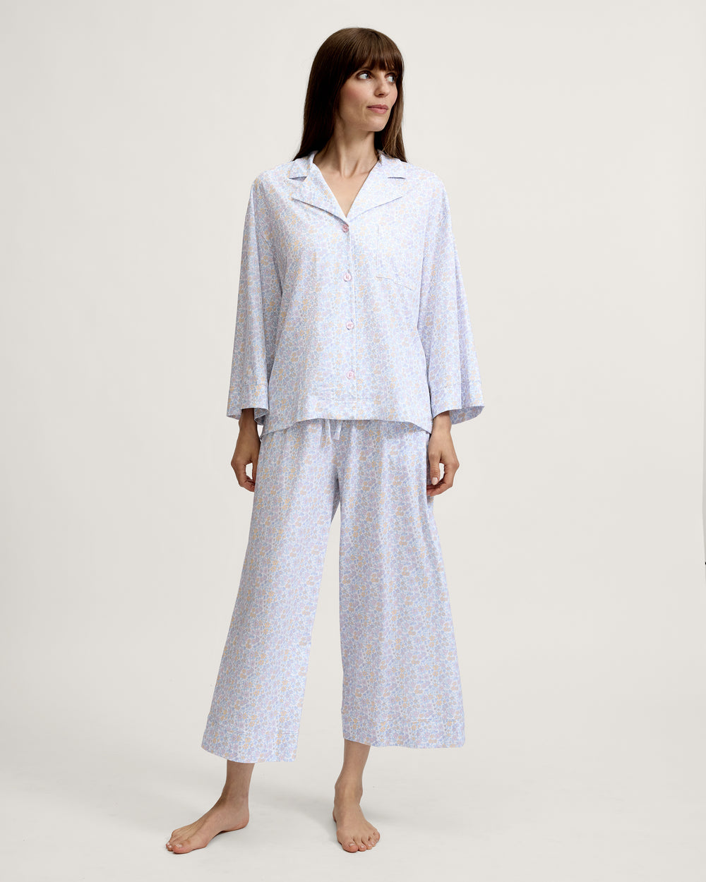 Woman wearing a light blue patterned pajama set on a white background