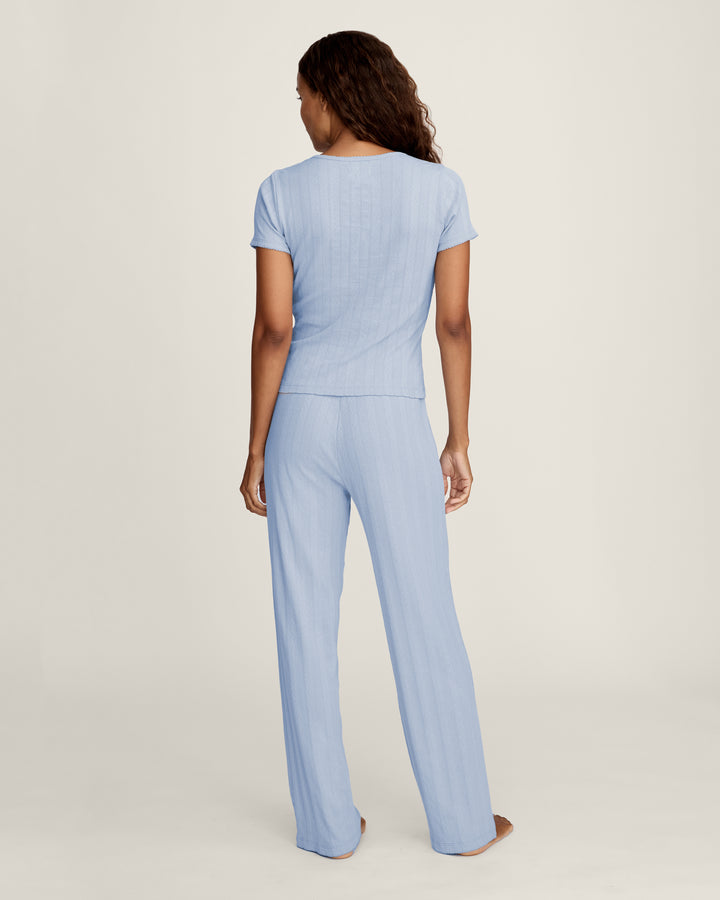 Woman wearing a light blue jumpsuit on a plain background