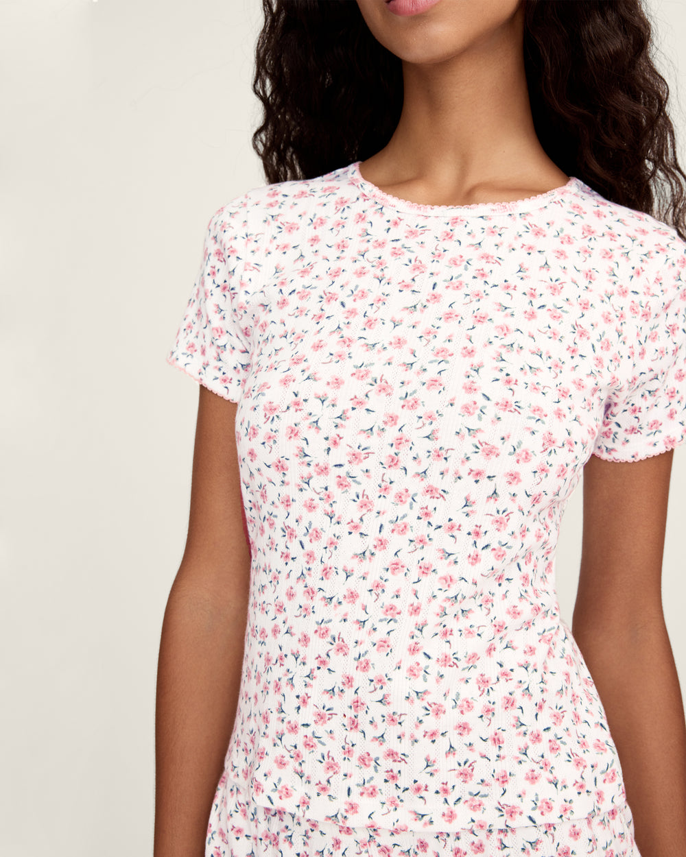 Woman wearing a white floral t-shirt against a plain background