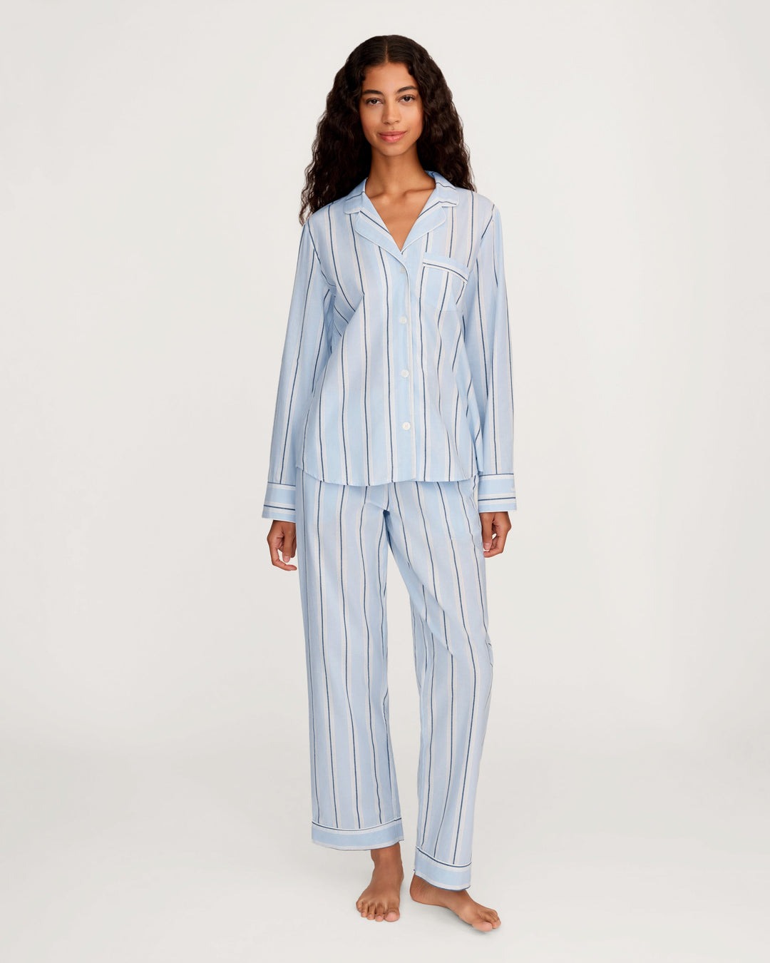 Woman wearing a light blue striped pajama set on a white background