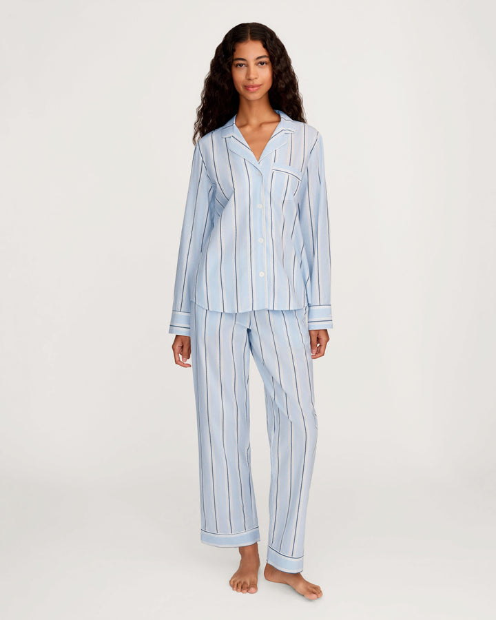 Woman wearing a light blue striped pajama set on a white background