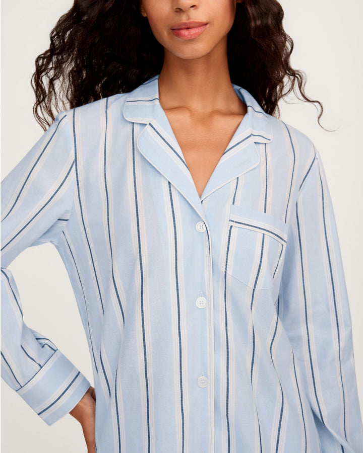 Woman wearing a light blue striped shirt against a white background