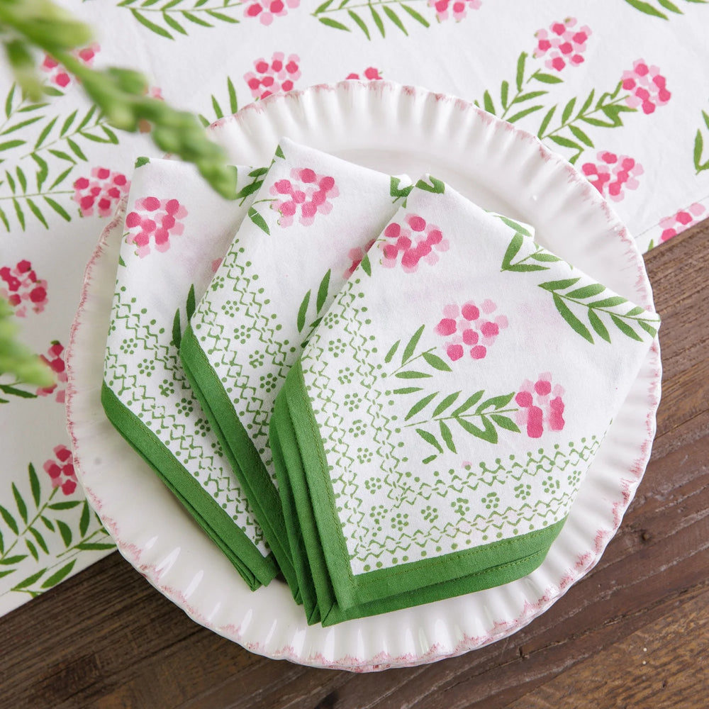 Set of paper plates and napkins with floral and leaf pattern on a wooden surface