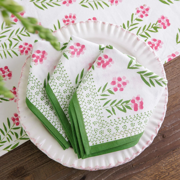Set of paper plates and napkins with floral and leaf pattern on a wooden surface