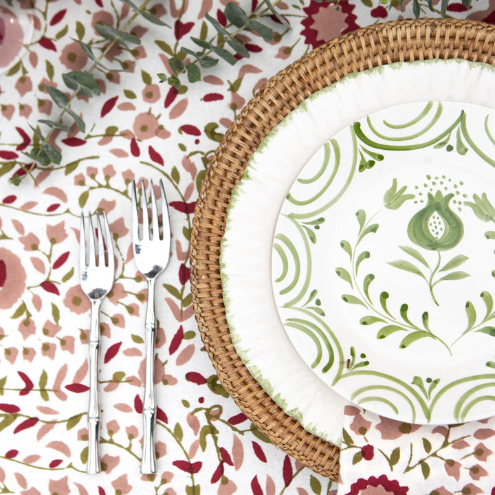 Table setting with floral tablecloth, wicker charger, and patterned plates.