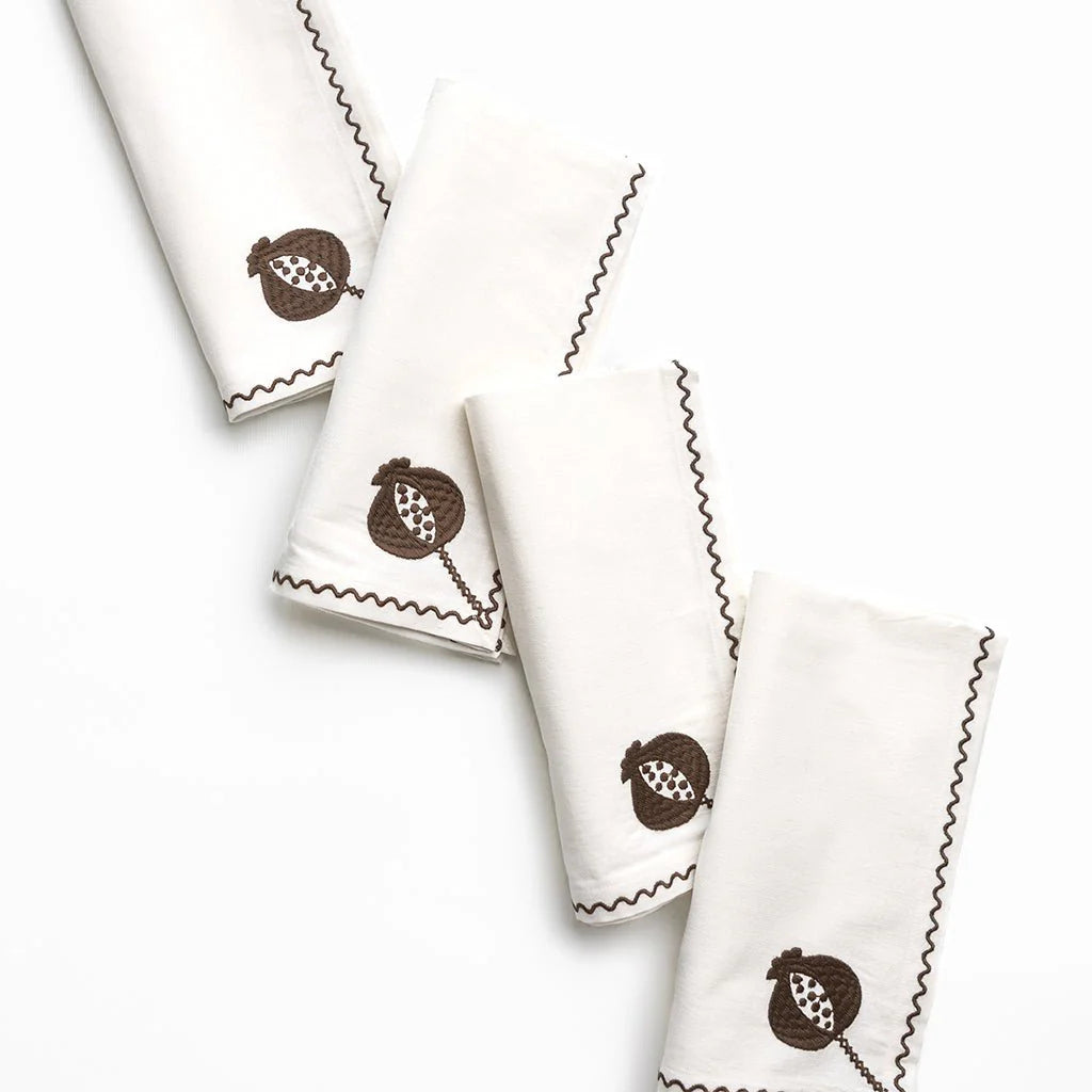 Set of white napkins with brown pomegranate designs on a white background