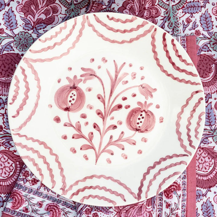 Decorative plate with pink floral design on a patterned fabric background
