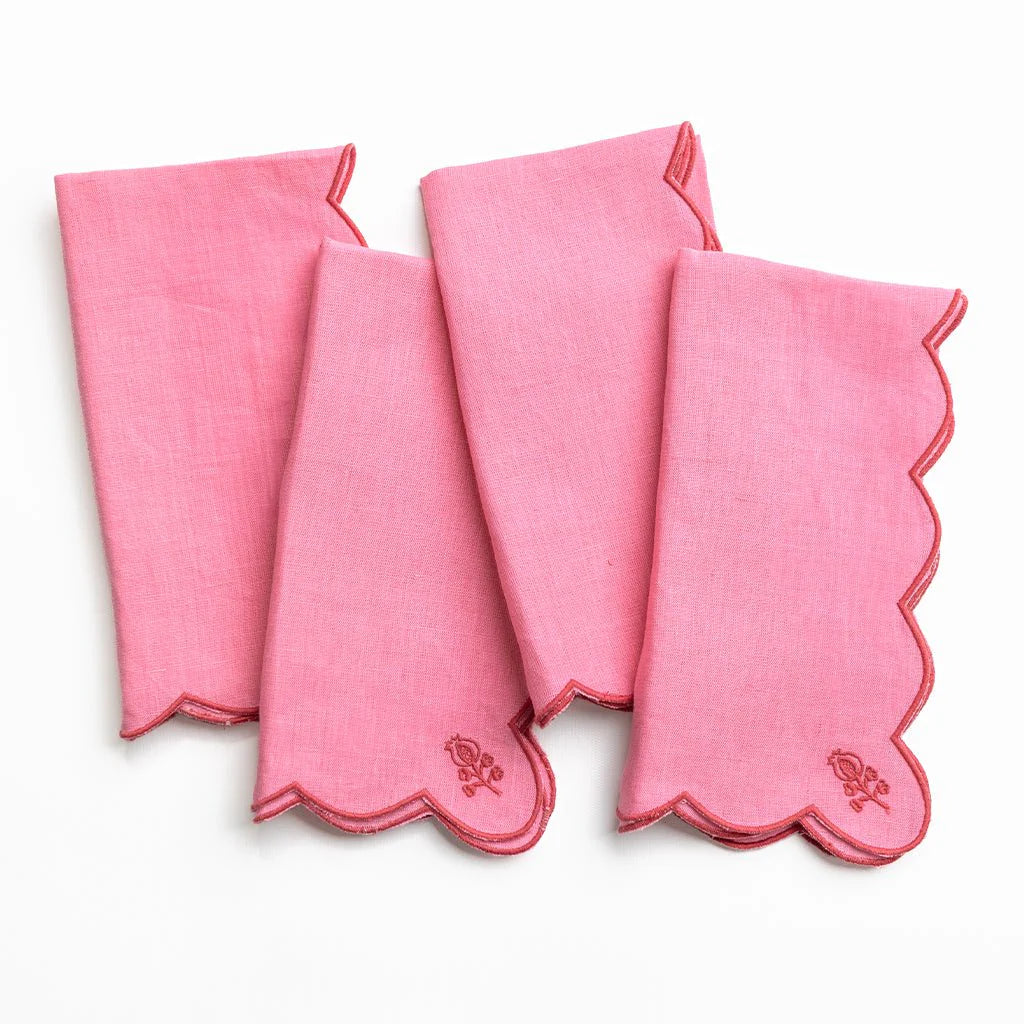 Set of four pink napkins with scalloped edges on a white background