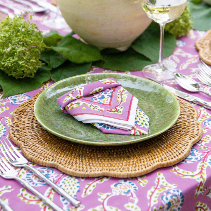 Table setting with green plates, colorful napkins, and a purple tablecloth.