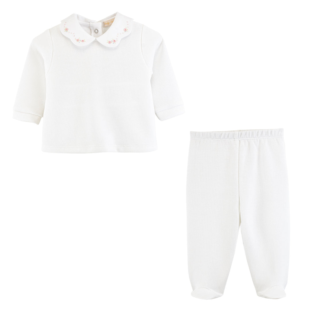 A two-piece baby clothing set in white, featuring a long-sleeve top with a Peter Pan collar decorated with small pink embroidered flowers, and matching white footed pants with an elastic waistband.