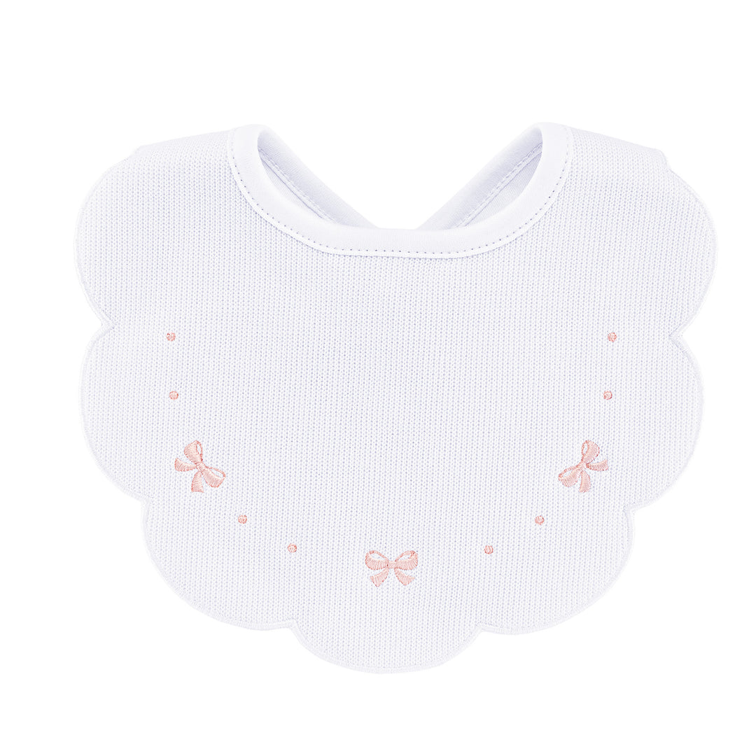 A white cotton baby bib with a scalloped edge, featuring three small pink embroidered bows and tiny pink dots on a plain white background.