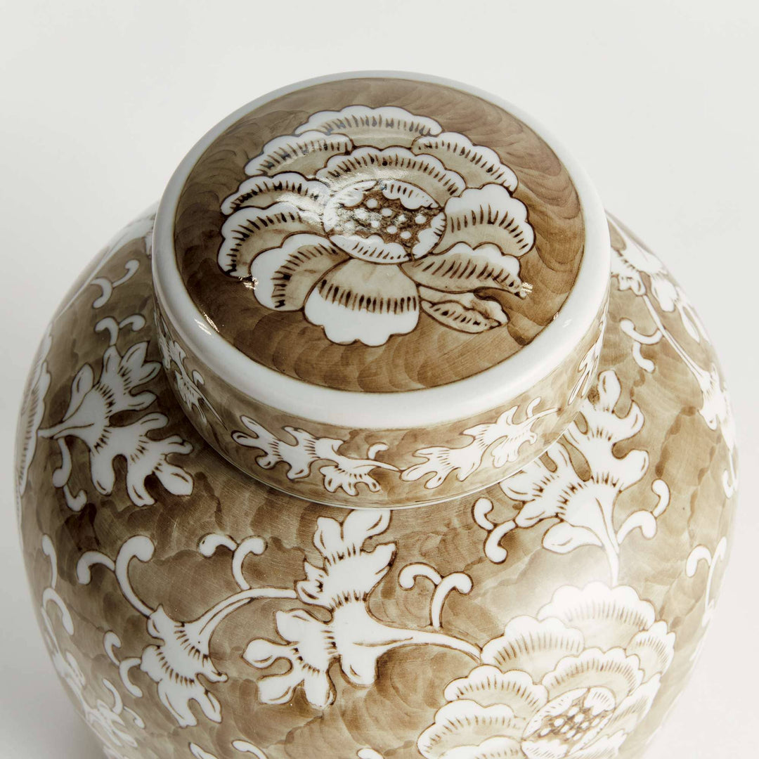 Decorative ceramic jar with intricate white floral patterns on a light background
