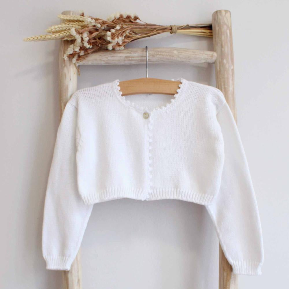 White sweater on a wooden hanger against a light background