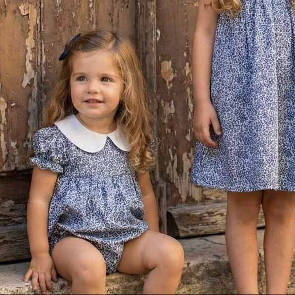 Three children in matching outfits standing in front of a rustic wooden door.