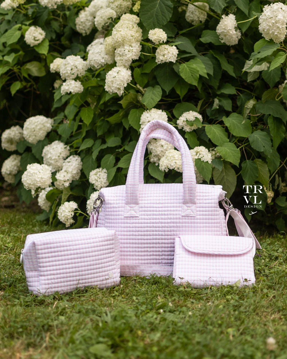 Set of baby bags sitting on grass in front of a hydrangea plant