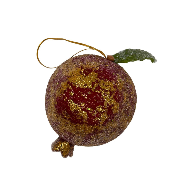 Decorative ornament resembling a fruit with gold and red glitter on a white background