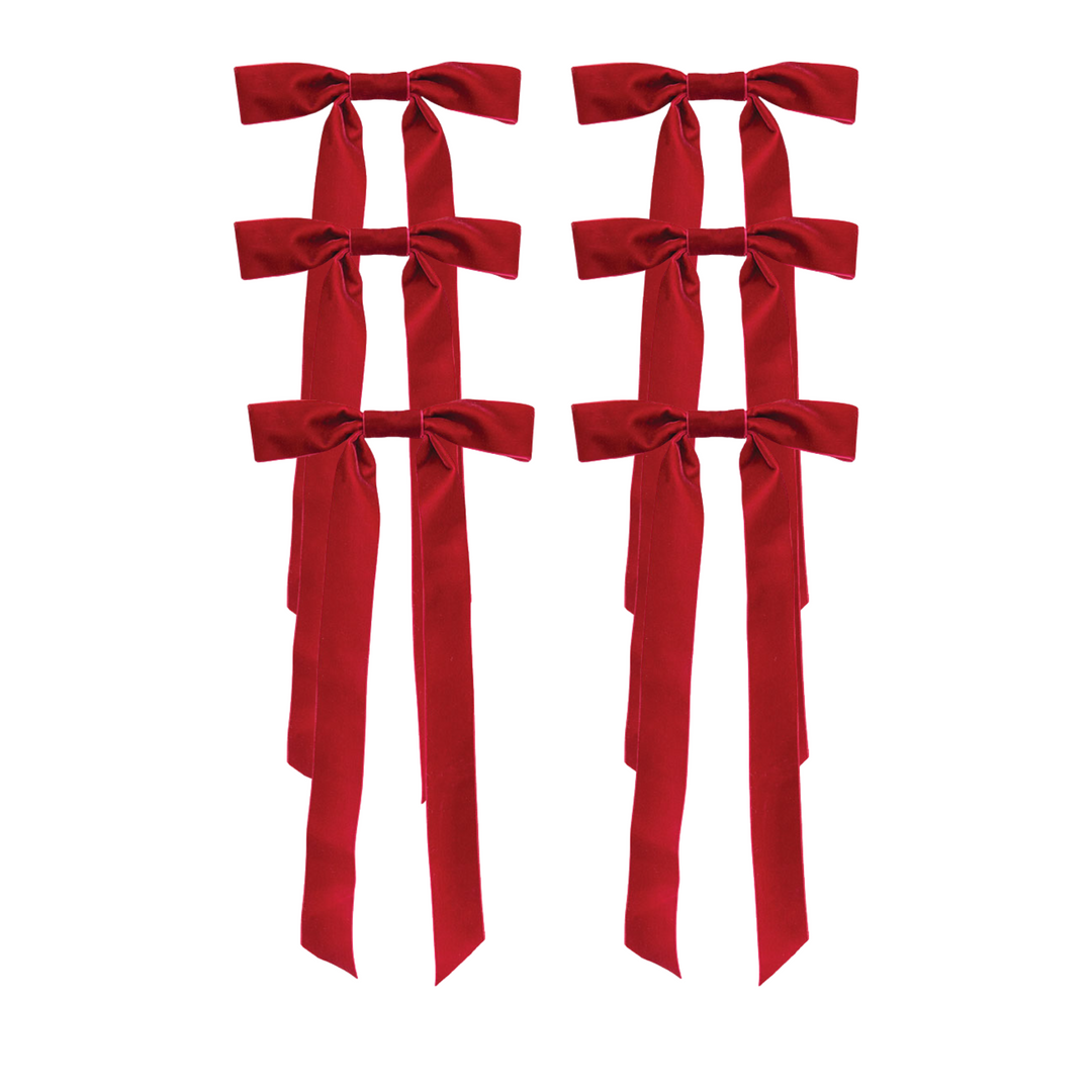 Four red velvet ribbon bows with long trailing ribbons, arranged in two pairs on a plain white background.