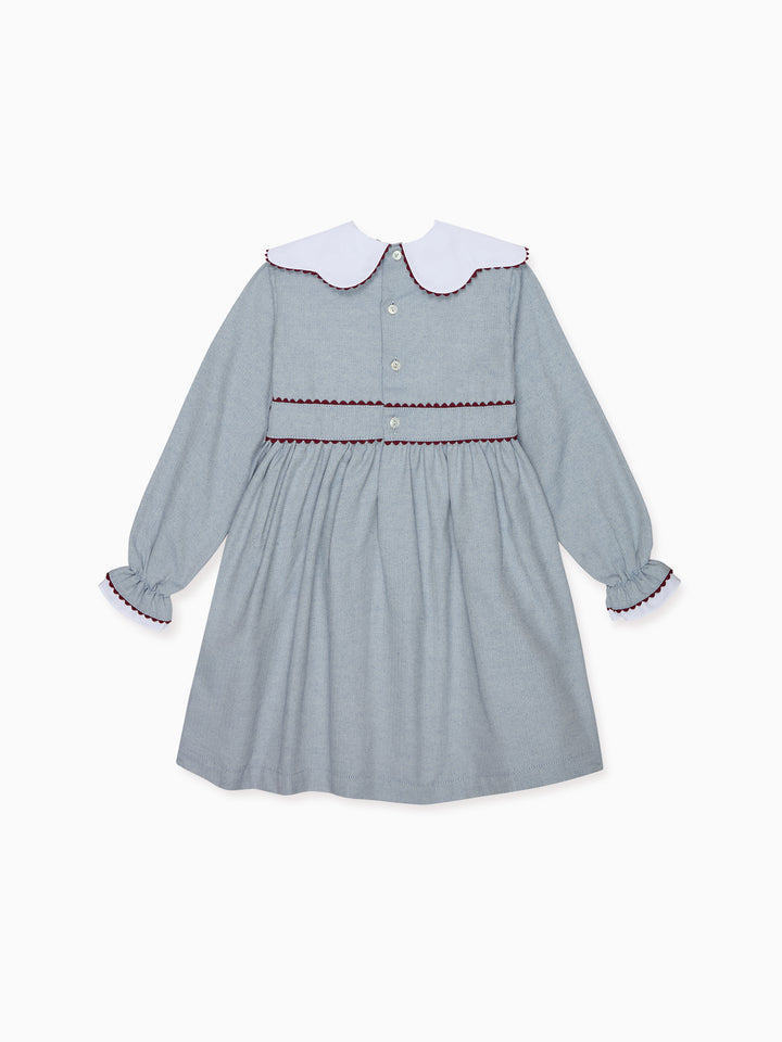 A light blue long-sleeve dress for toddlers, featuring a contrasting white Peter Pan collar with red trim, a buttoned front, and a matching red-trimmed waistband.