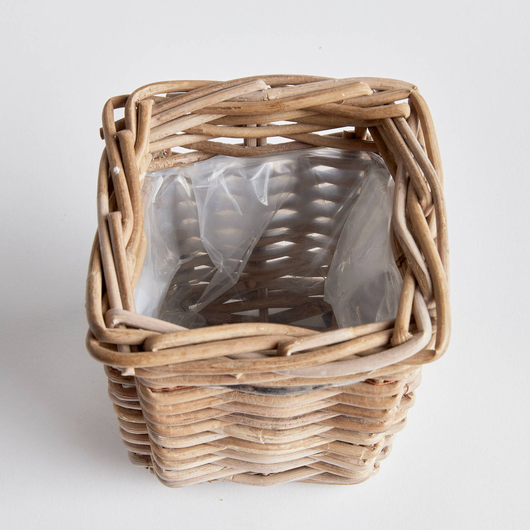 Woven basket with a clear plastic bag inside on a white background