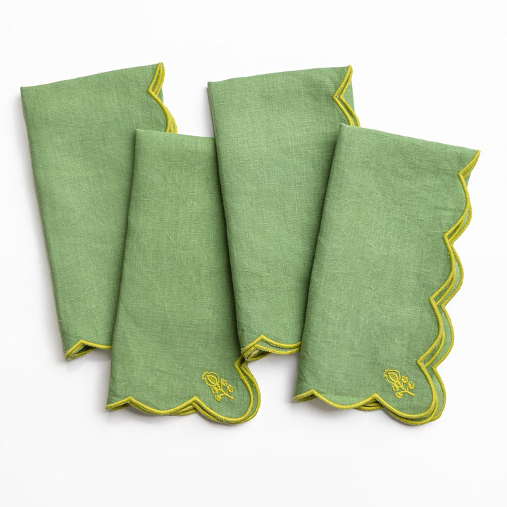 Set of four green napkins with yellow trim on a white background