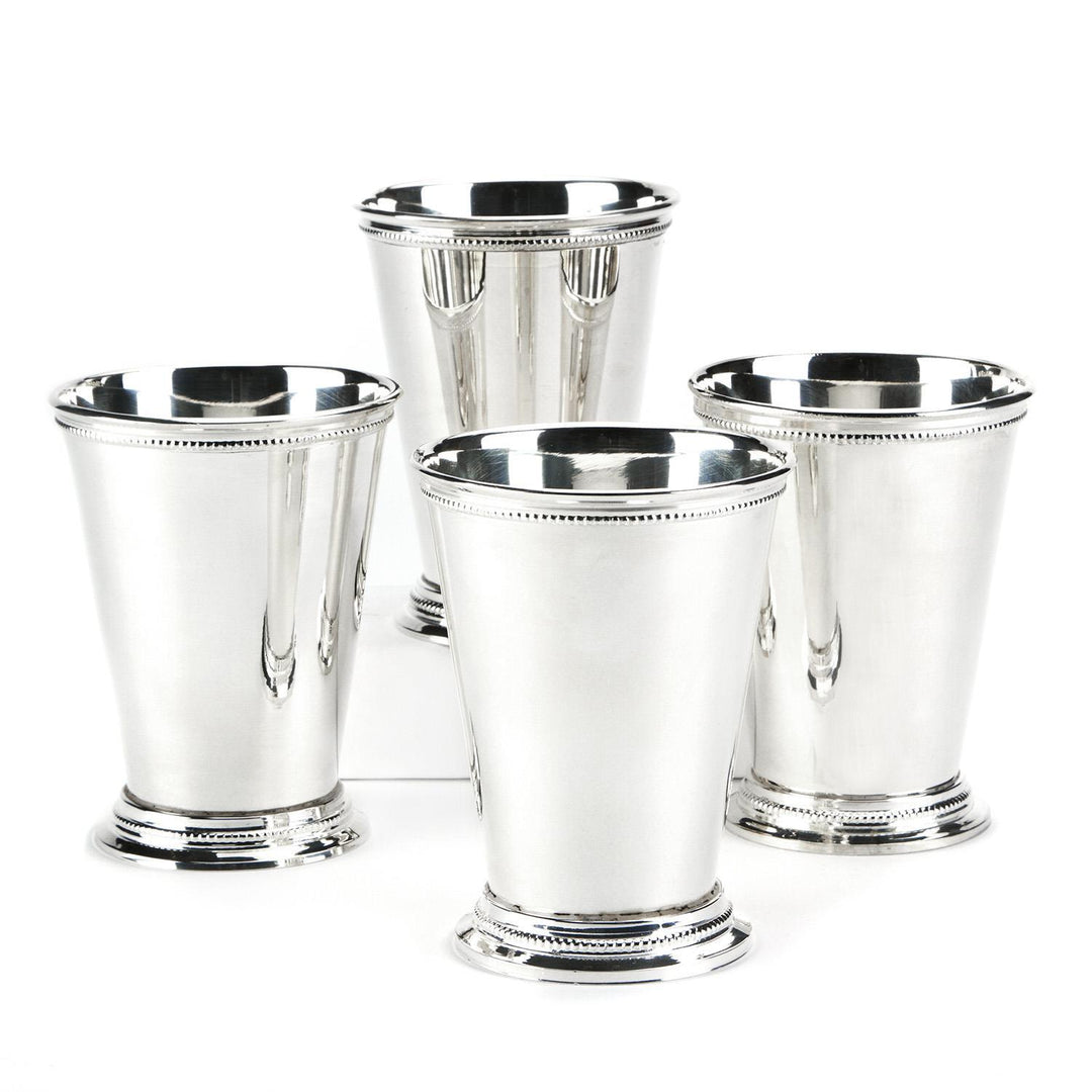 Set of four silver mint julep cups on a white background