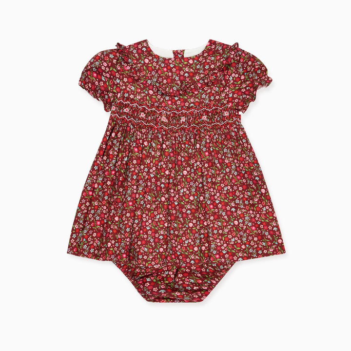 A baby girl dress in a red and green floral print, featuring short ruffled sleeves and a smocked bodice, laid flat against a white background.