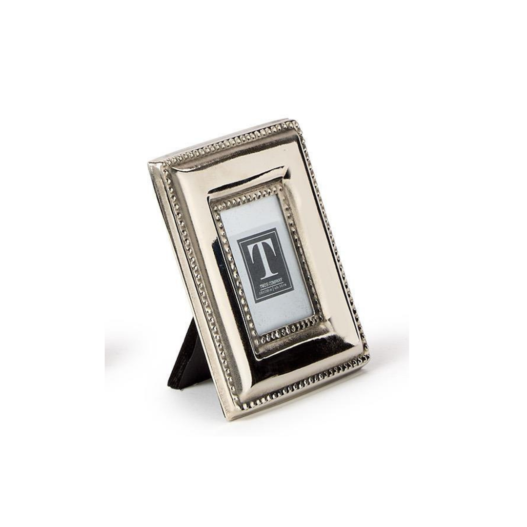A small rectangular silver picture frame with a decorative beaded border and a black triangular stand, shown on a white background.