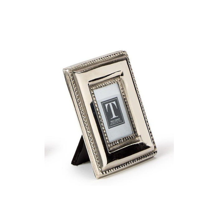 A small rectangular silver picture frame with a decorative beaded border and a black triangular stand, shown on a white background.