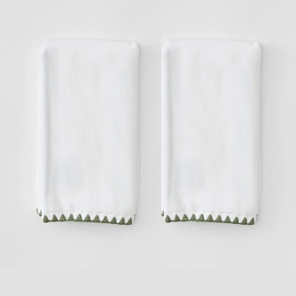 Two folded white towels with a green zigzag border along the bottom edge, displayed side by side on a light gray background.