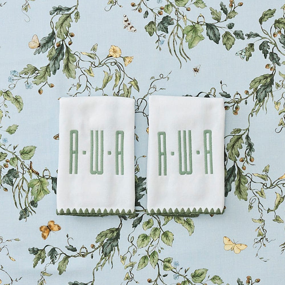 Two folded white towels with green embroidered monogram letters 'A.W.
