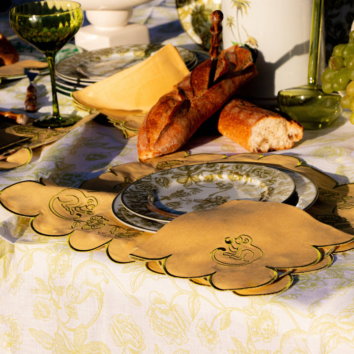Table setting with bread, cheese, and wine glasses on a decorative tablecloth.