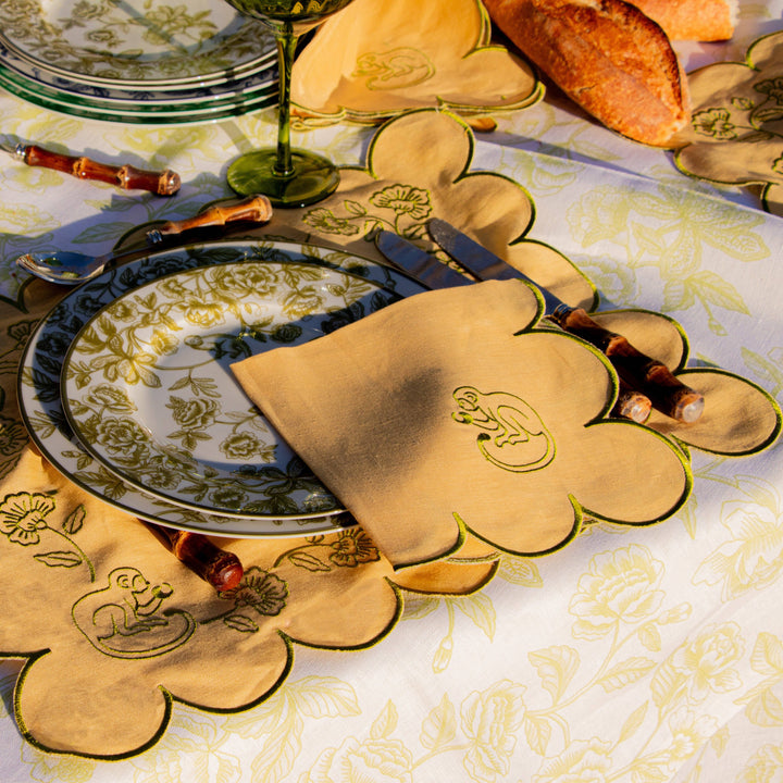 Decorative table setting with floral-patterned placemats and cutlery on a tablecloth.